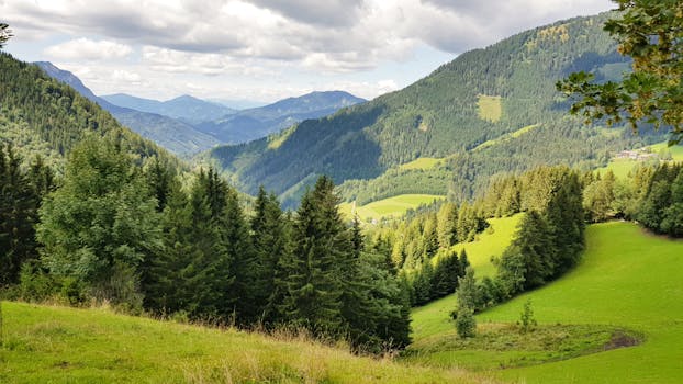 Breathtaking view of green valleys and mountains under a cloudy sky.
