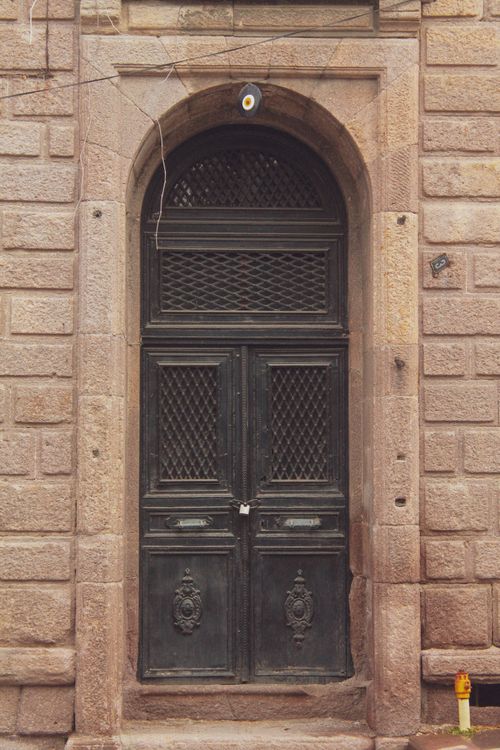Free A classic arched wooden door set in a brick wall, featuring intricate designs, exuding historical charm. Stock Photo