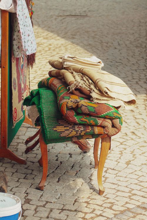 Free Stack of colorful handcrafted rugs on a vintage wooden chair outdoors. Stock Photo