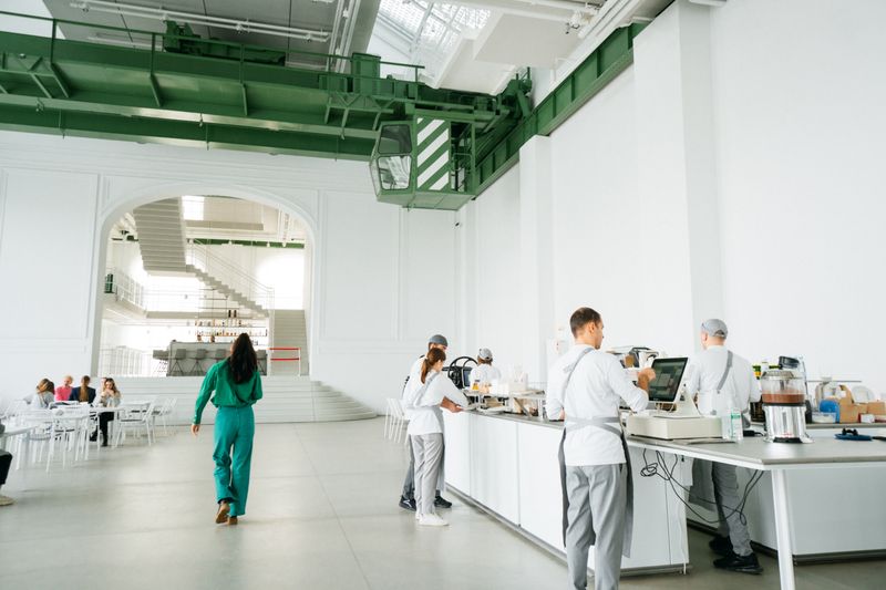 A spacious modern cafeteria with staff in white uniforms serving customers in Moskva, Russia.