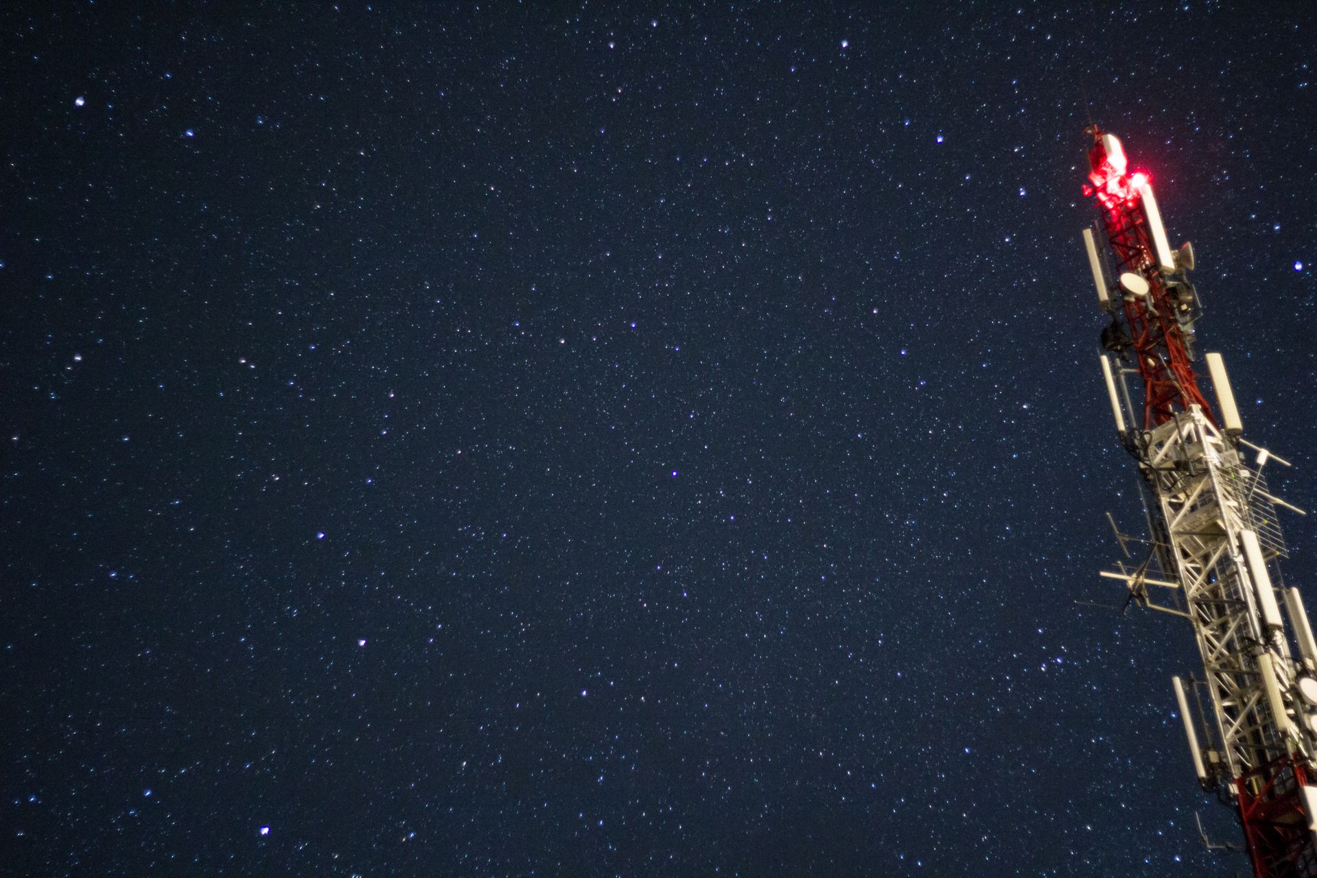 A starry night sky featuring a lit radio tower, capturing celestial beauty and communication technology.