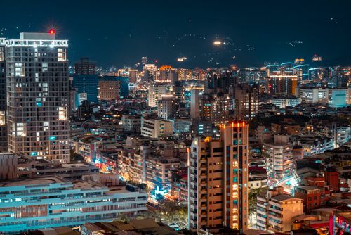 Free A vivid aerial cityscape featuring glowing urban lights and towering buildings at night. Stock Photo