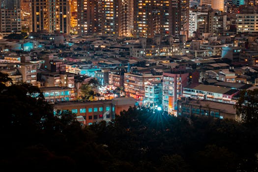 A striking aerial night view of a densely packed urban cityscape with illuminated buildings.