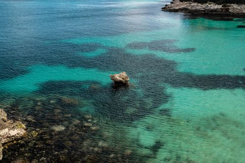 Free Calm ocean view with striking turquoise and dark blue waters featuring unique rock formations. Stock Photo