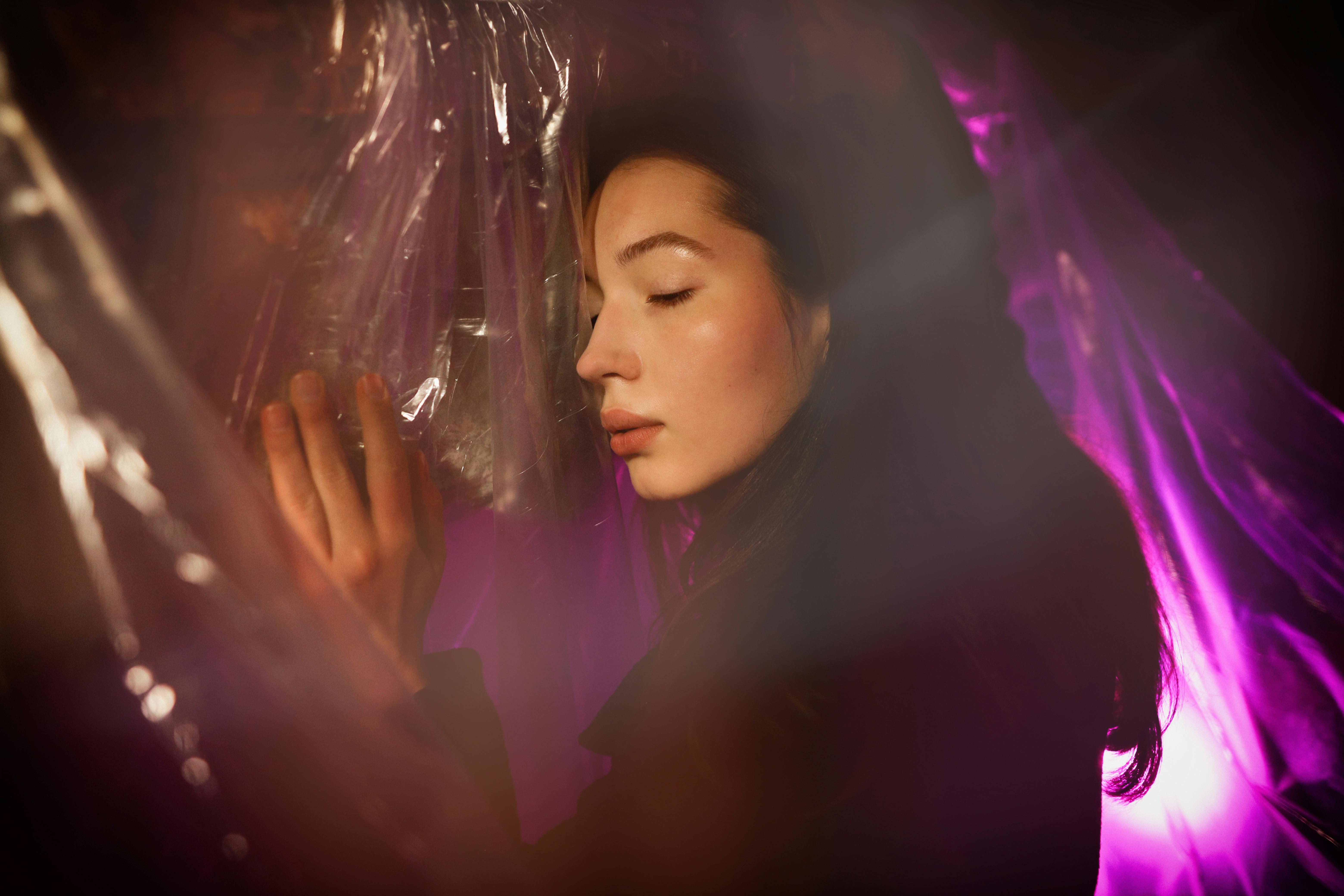 Woman with eyes closed enveloped in pink ethereal light, peaceful expression of complete dreamy surrender