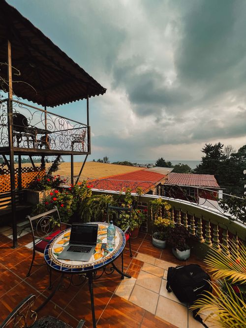 Free A cozy rooftop patio with table, laptop, and plants, perfect for remote work. Stock Photo