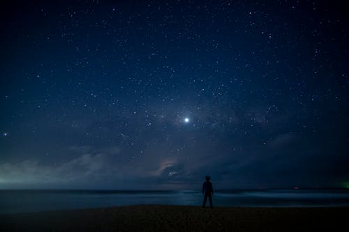 Free 
A Silhouette of a Man Standing under a Starry Night Sky Stock Photo