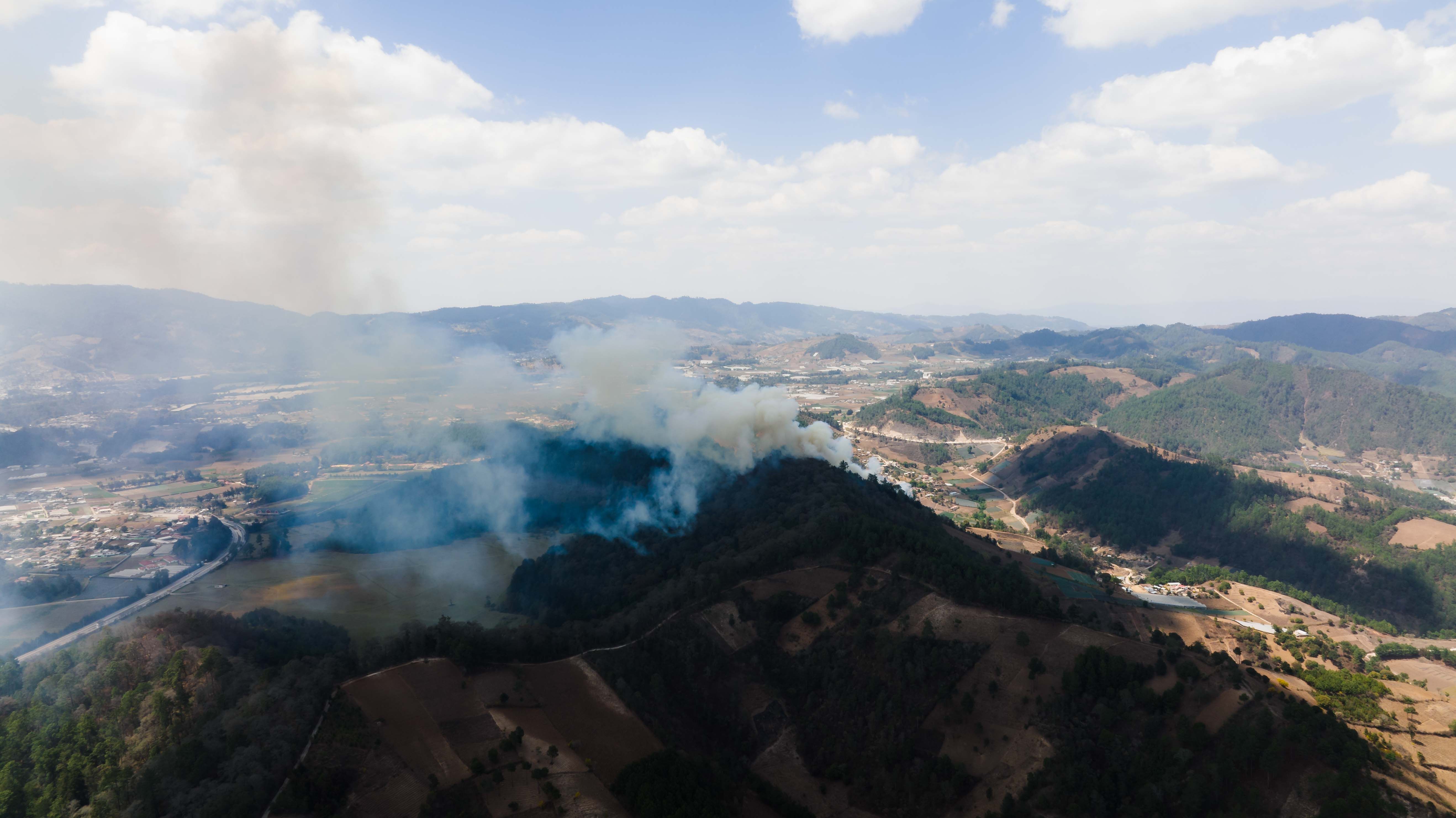 Drone-perspective view of smoke rising from forest fire