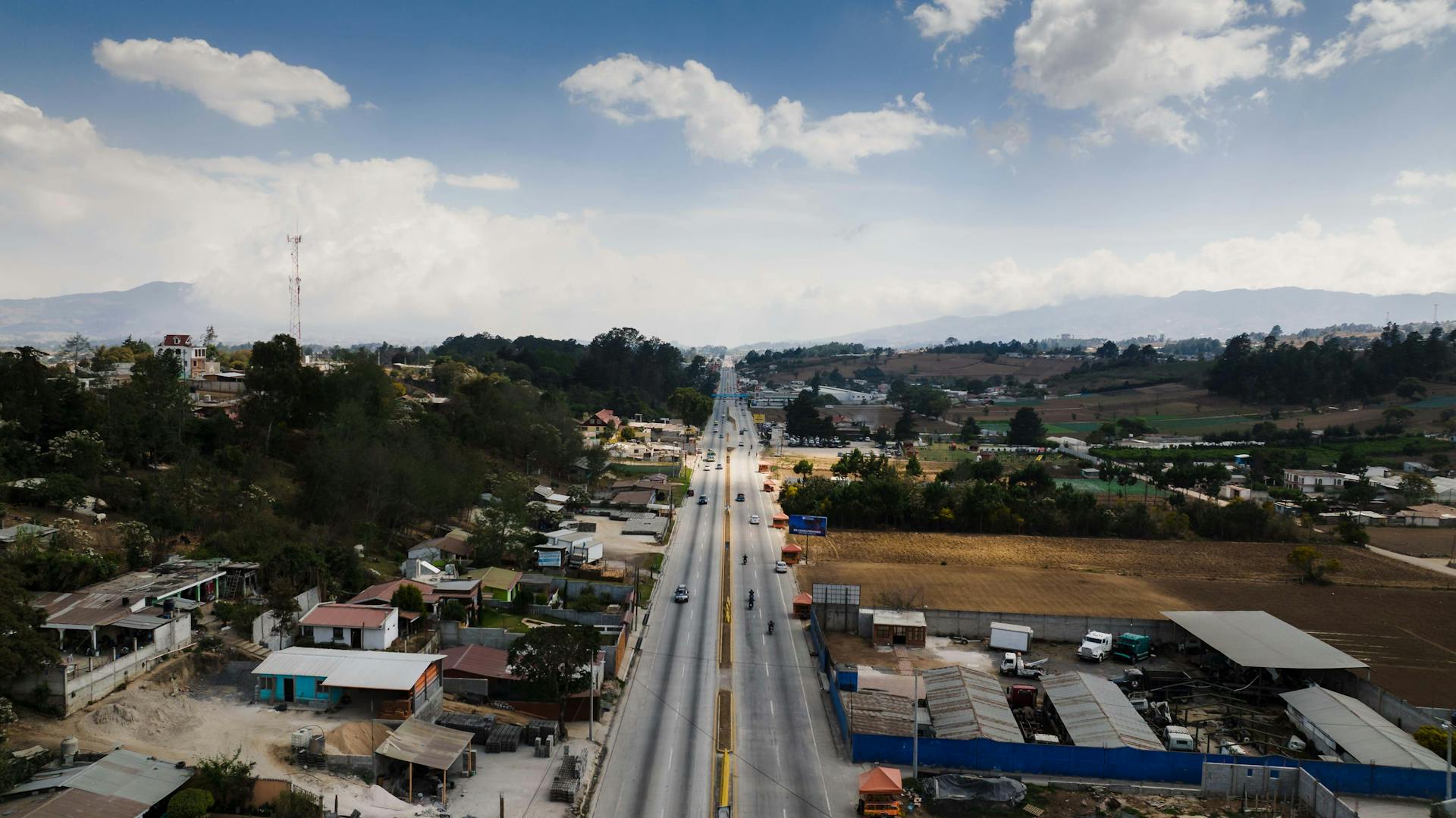 Drone shot of a highway cutting through rural countryside with small communities on either side.