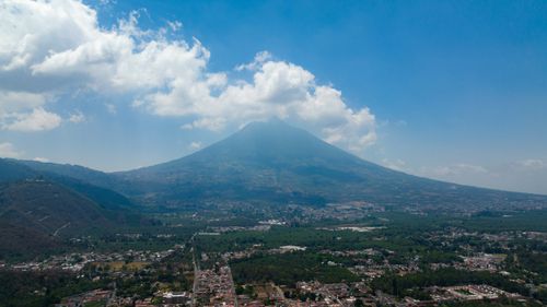 Free A stunning view of a towering volcano surrounded by a scenic town and lush greenery under a bright sky. Stock Photo