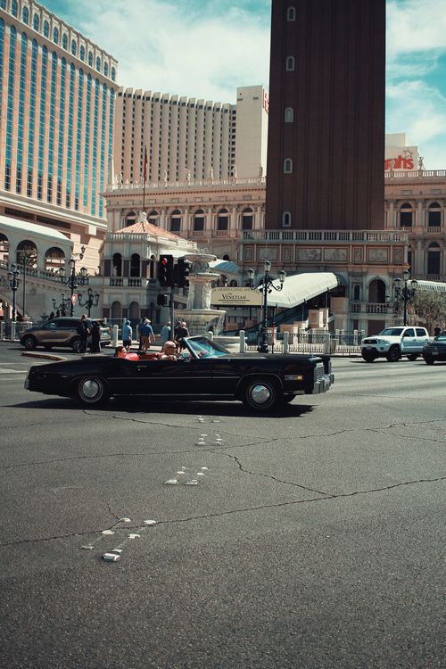 Free A classic black convertible car driving past the Venetian Hotel in Las Vegas on a sunny day. Stock Photo