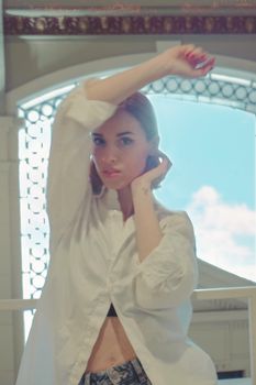 Woman modeling in a white shirt with arm raised, capturing elegance and style.