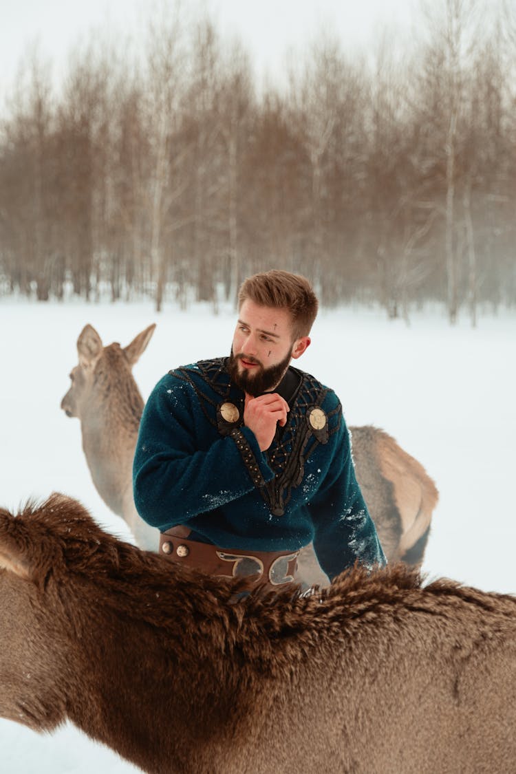 Man Standing In Snow With Deer