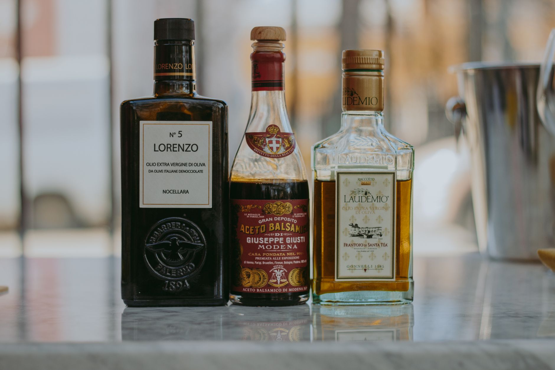 Elegant display of olive oil and balsamic vinegar bottles on a marble surface.