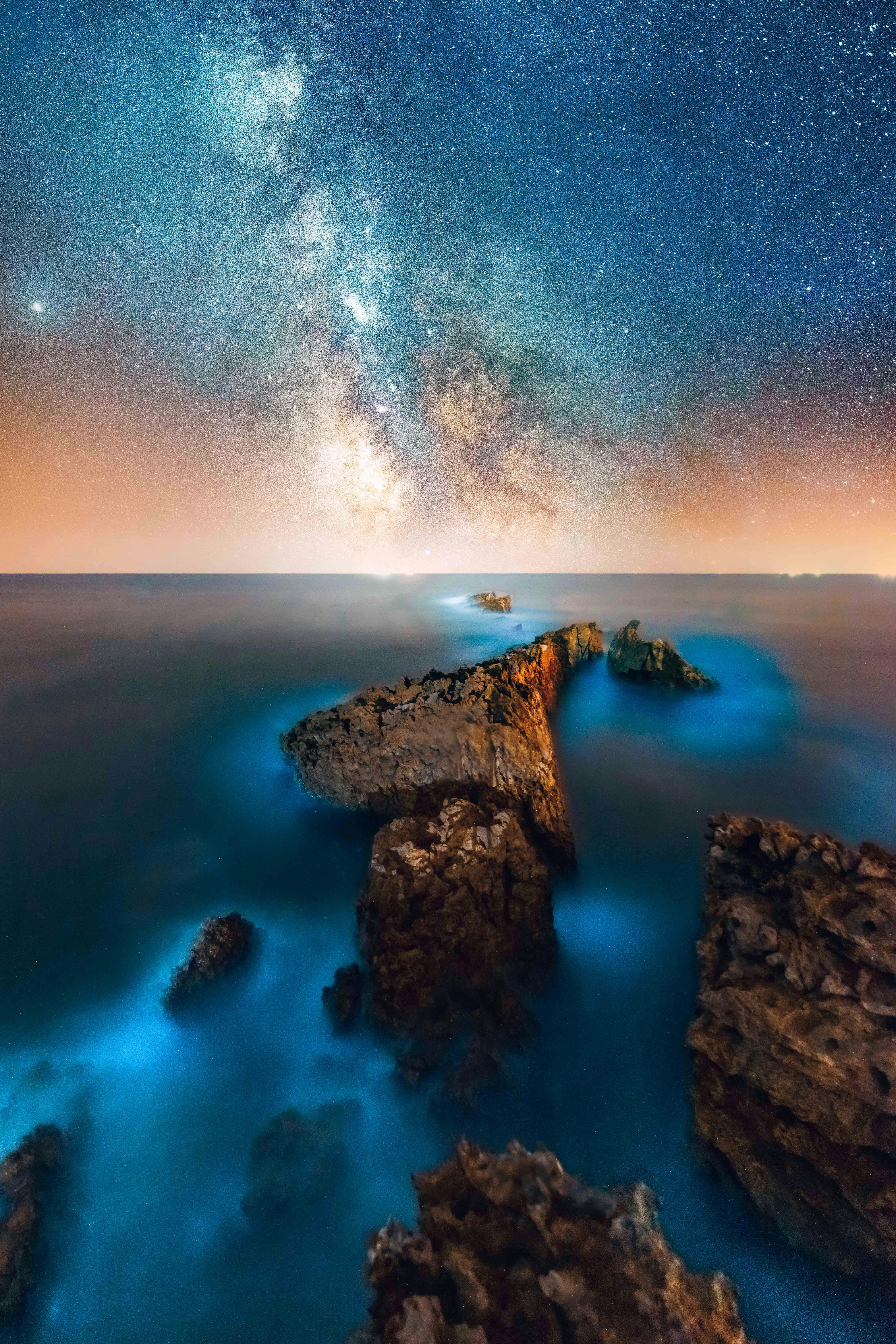 Stunning view of the Milky Way galaxy over rocky sea coast in Pakistan, showcasing celestial and natural beauty.