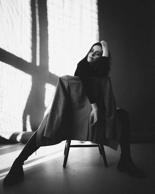 Free A Grayscale Photo of a Woman Sitting on a Chair Stock Photo