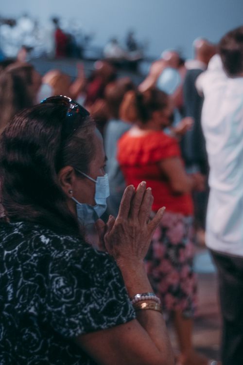 Free A group of people in a religious gathering, some wearing face masks, praying indoors. Stock Photo