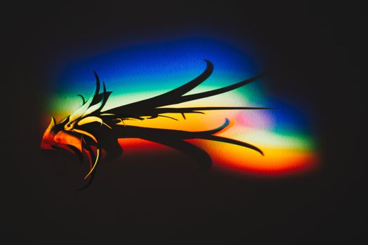 Colorful abstract light pattern creating dynamic shadows on a dark surface.