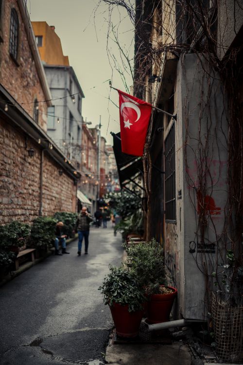 Free Narrow alleyway in Turkey adorned with national flags and plants, offering urban charm. Stock Photo