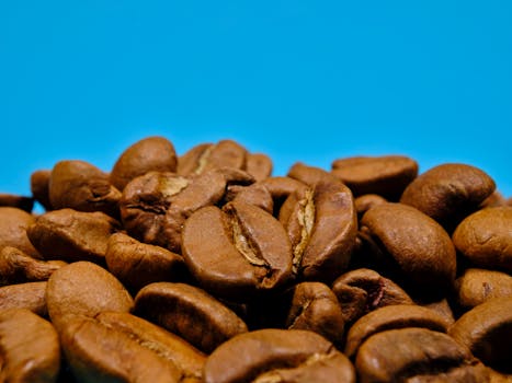 A detailed close-up of roasted coffee beans against a vibrant blue background, emphasizing their texture and color.