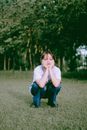 Woman in White Long Sleeve Shirt and Blue Denim Jeans Sitting on Green Grass Field during