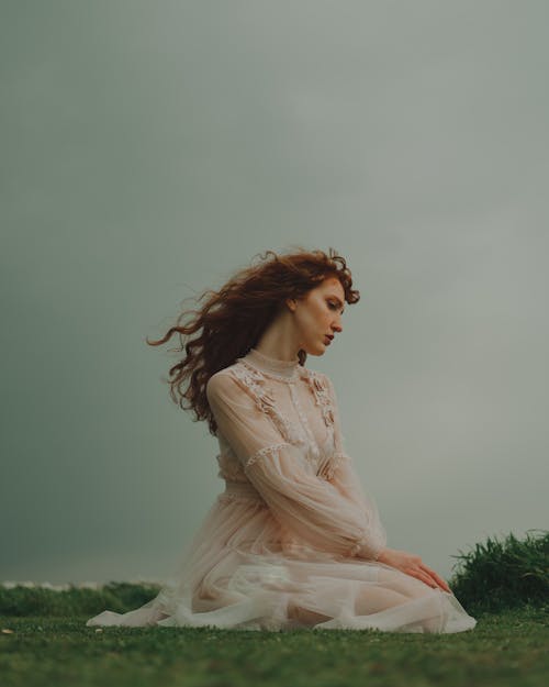 Woman Sitting on Grass in White Boho Dress