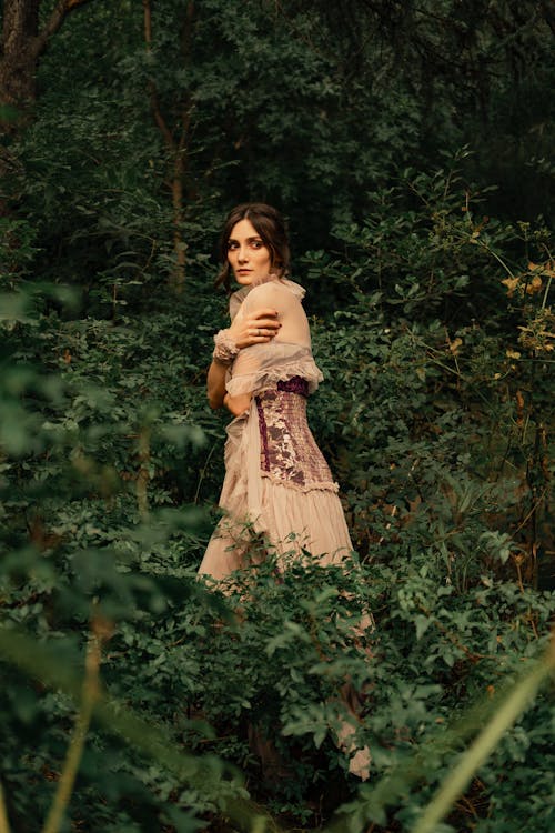 Woman in Beige Dress Standing in the Middle of a Forest