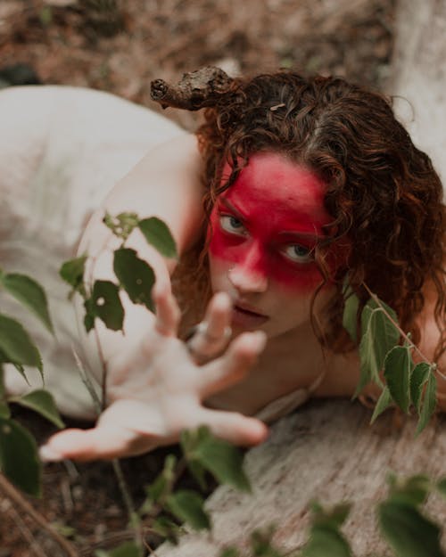 Woman in Red Face Paint Lying on Ground 