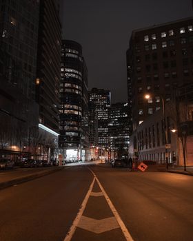 A serene view of downtown Vancouver at night with illuminated skyscrapers and empty streets.