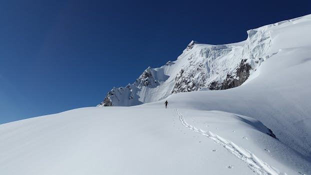 一个人在晴朗的蓝天下徒步穿越白雪皑皑的风景