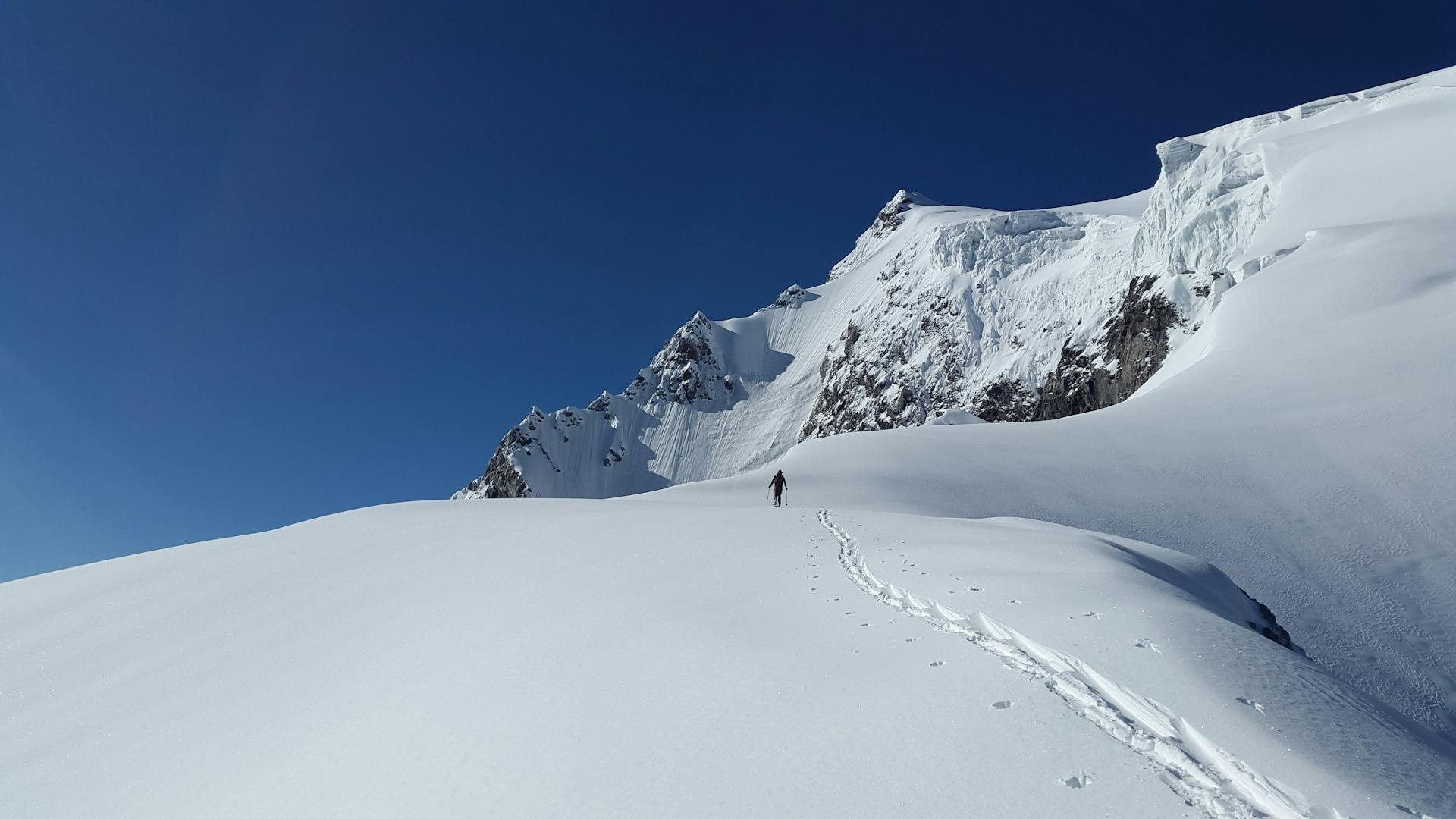 Man Walking in White Mountain Snow during Daytime