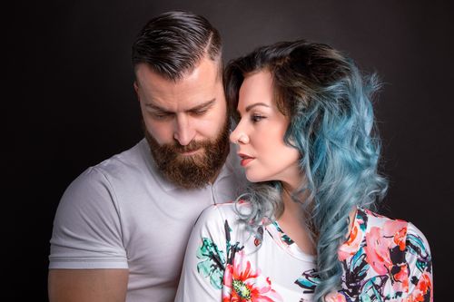 Free A couple embracing in a studio setting with a gray background, showcasing intimacy and style. Stock Photo