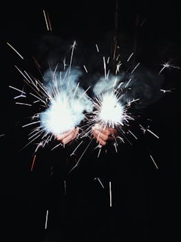 在黑暗背景下，一只手持明亮火花的手冒出烟雾和火花