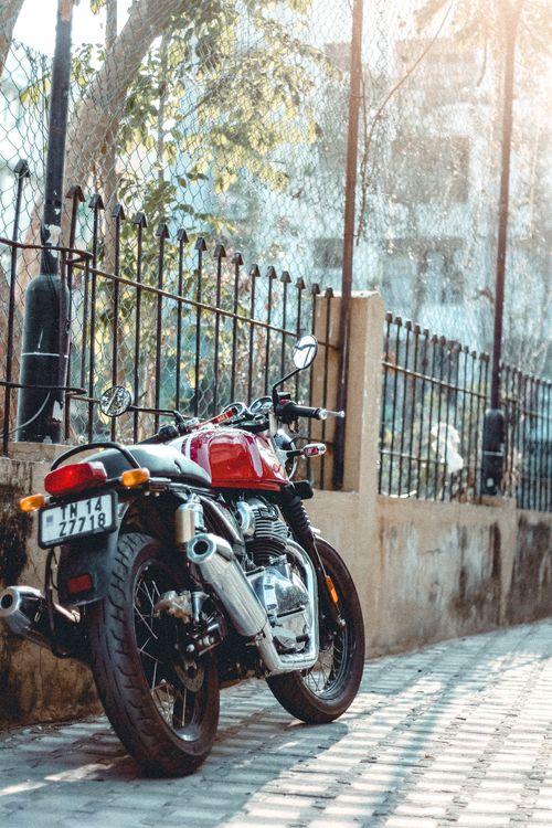 Free A stylish Royal Enfield motorbike parked outdoors on a sunny day alongside a sidewalk. Stock Photo