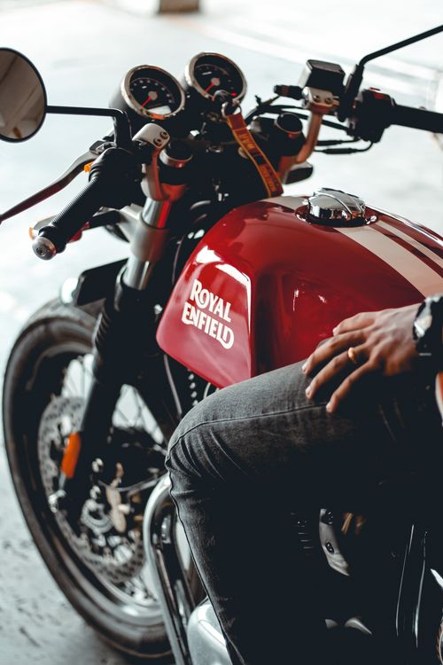 Free Close-up of a man riding a red Royal Enfield motorbike indoors, focusing on details. Stock Photo