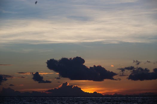 A stunning sunrise over the ocean with dramatic dark clouds and vibrant colors.
