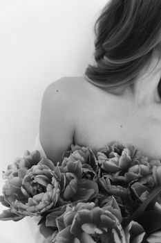 Elegant black and white portrait of a woman adorned with flowers against a white background.
