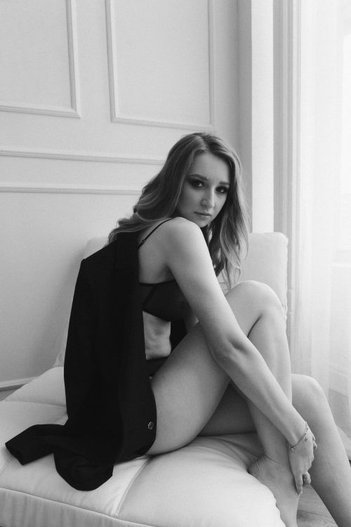 Free Black and white portrait of a woman sitting on a couch indoors, exuding elegance and style. Stock Photo