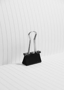 A close-up of a black binder clip on lined paper, showcasing office simplicity.