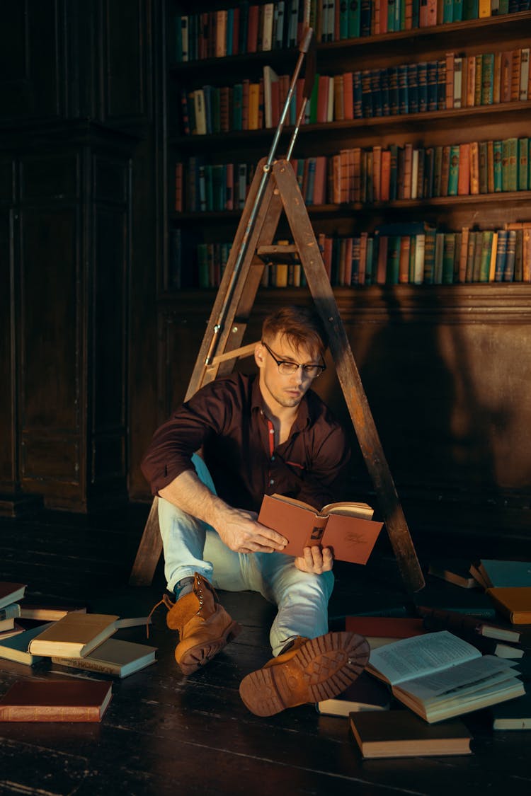 Man Sitting On Floor Surrounded By Books Studying