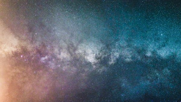 Vista deslumbrante da galáxia Via Láctea à noite, exibindo inúmeras estrelas e cores cósmicas.