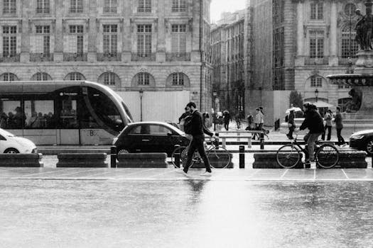 Black and white photo of a city street with rain, bicycles, and a tram passing by.