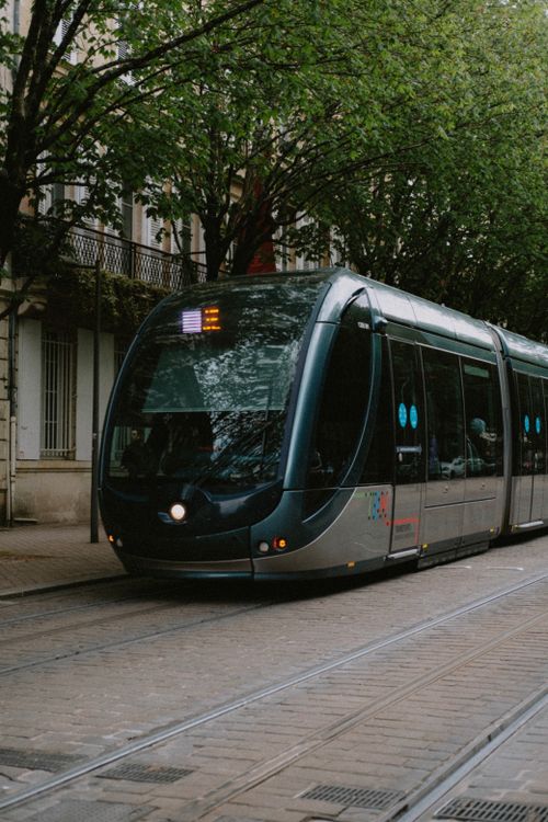 Free A sleek tram travels along a tree-lined street in Bordeaux, France, showcasing urban public transportation. Stock Photo