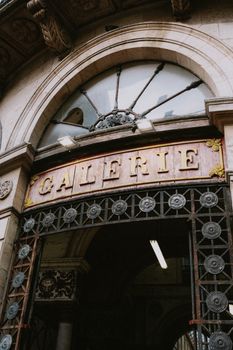 An ornate archway entrance to a historic French galerie with vintage signage.