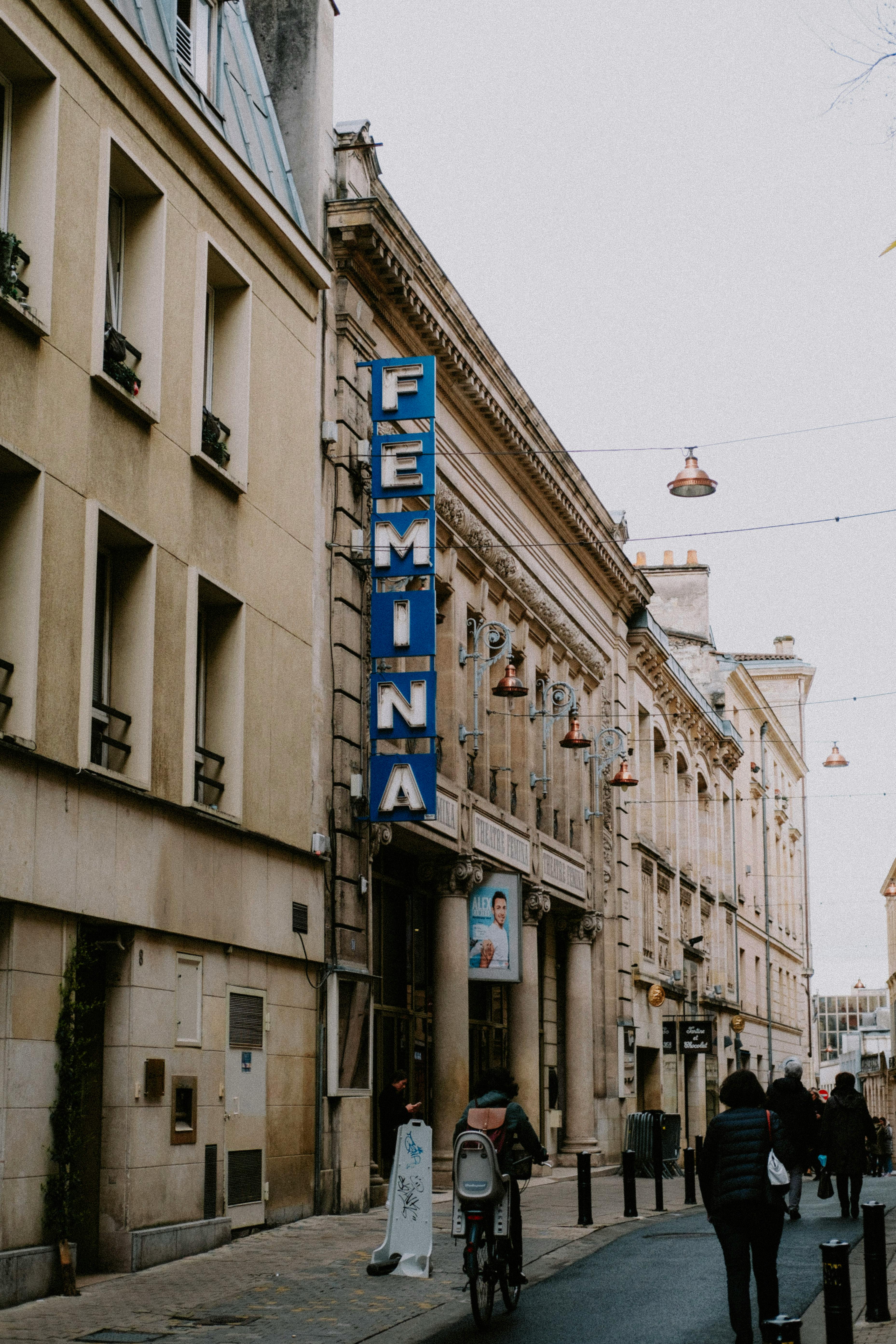 Free A bustling city street with a prominent FEMINA theater sign and people walking by. Stock Photo