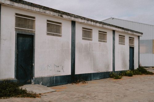 Free An exterior view of an abandoned industrial building with weathered walls and doors. Stock Photo
