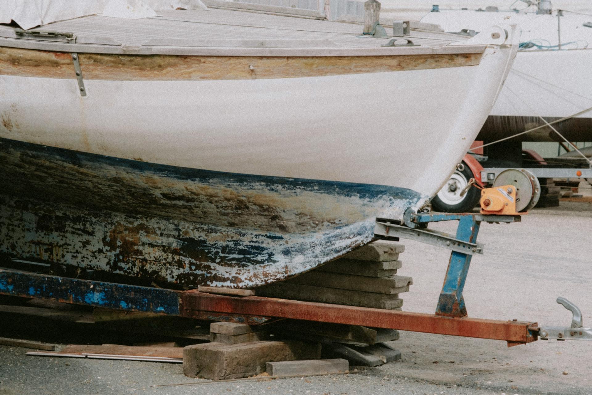 A weathered boat in a marina, showing signs of damage and renovation work.