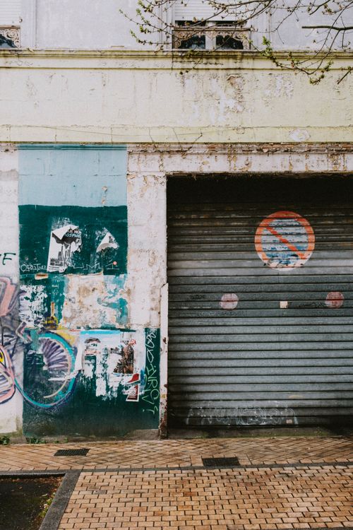 Free Facade of a vandalized building with graffiti and a roll-up door. Stock Photo