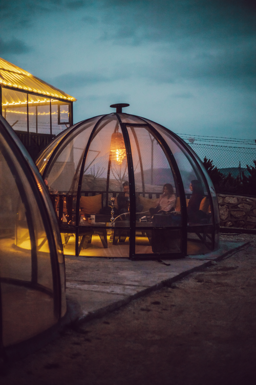 Free A person relaxes inside a warmly lit glass dome at night, showcasing modern architecture. Stock Photo