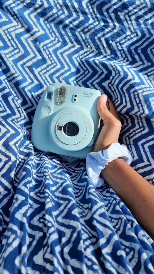 Hand Holding a Polaroid Camera on a Blanket